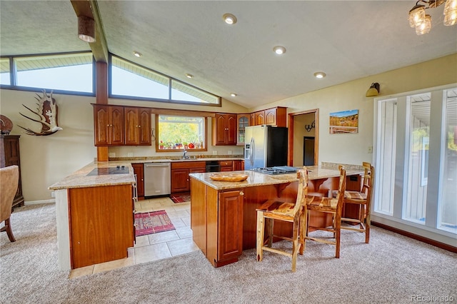 kitchen featuring a kitchen island, appliances with stainless steel finishes, lofted ceiling with beams, a breakfast bar, and light colored carpet