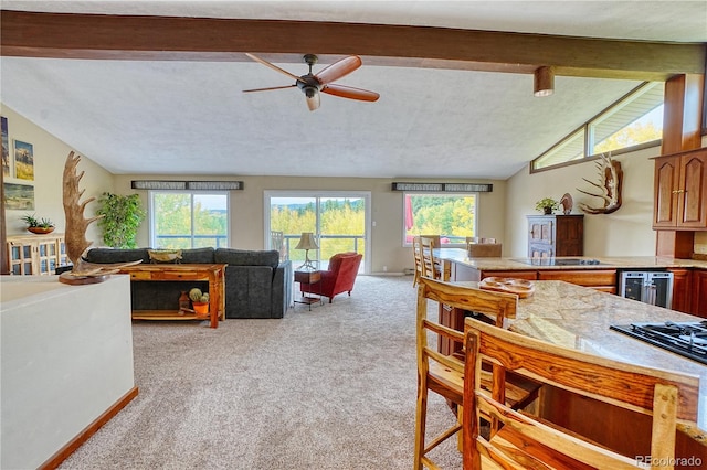 dining space with ceiling fan, light colored carpet, a textured ceiling, and lofted ceiling with beams