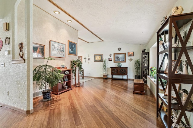 interior space with baseboards, lofted ceiling, a textured ceiling, and wood finished floors