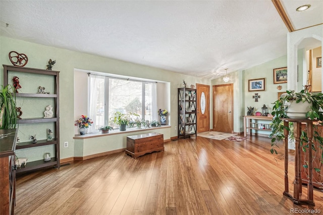 entrance foyer with baseboards, a textured ceiling, vaulted ceiling, and hardwood / wood-style flooring