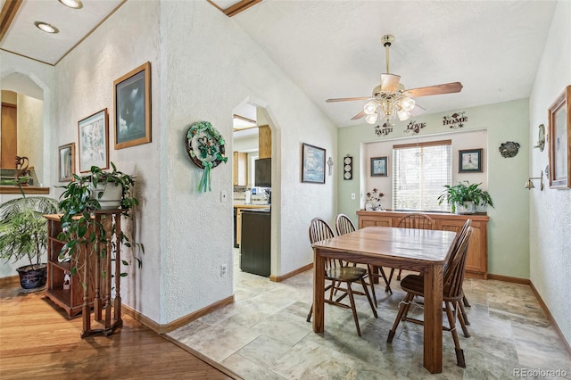 dining space with arched walkways, baseboards, ceiling fan, and a textured wall