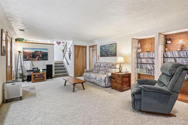 carpeted living room featuring stairway, a textured ceiling, and visible vents