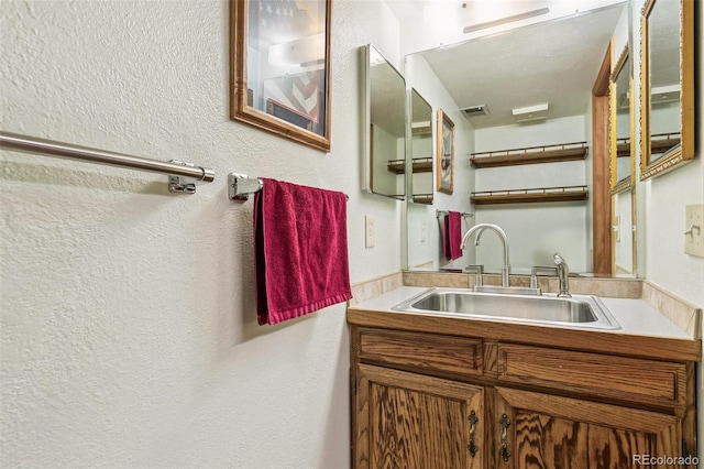 bathroom with vanity and a textured wall