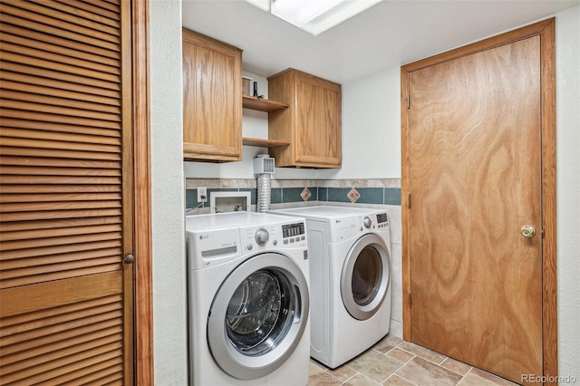 laundry room featuring washer and dryer, cabinet space, and stone finish flooring