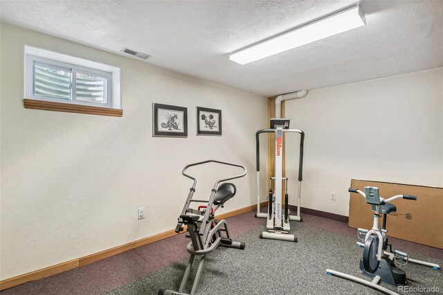 exercise room featuring visible vents, baseboards, and a textured ceiling