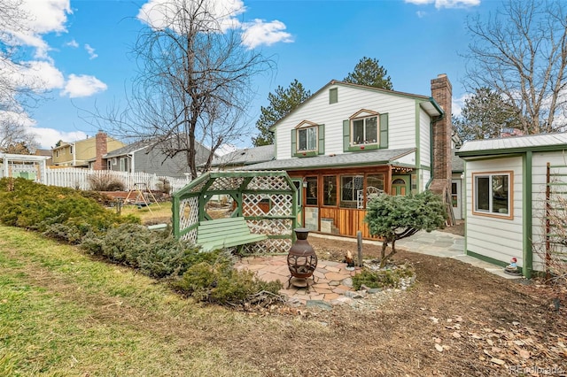 back of house featuring a patio, fence, a chimney, and an outdoor fire pit