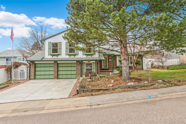 split level home with concrete driveway, an attached garage, fence, and brick siding