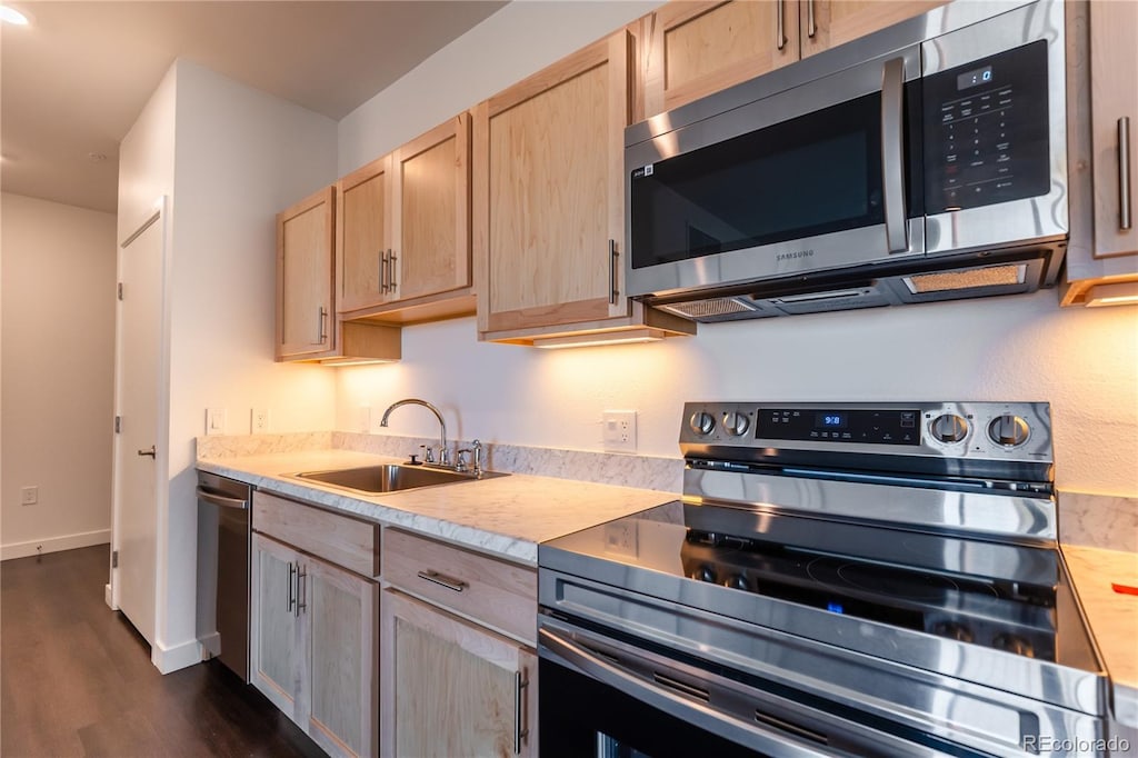 kitchen with appliances with stainless steel finishes, dark hardwood / wood-style flooring, light brown cabinetry, and sink