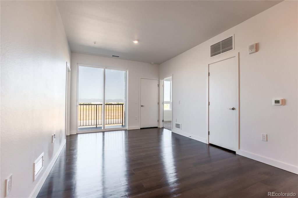 empty room featuring a healthy amount of sunlight and dark hardwood / wood-style floors