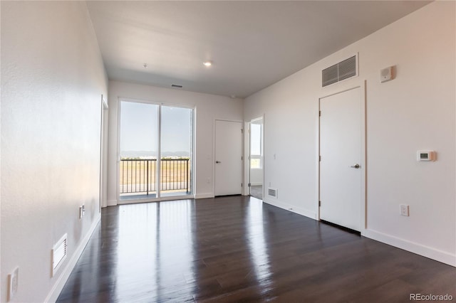 empty room featuring a healthy amount of sunlight and dark hardwood / wood-style floors