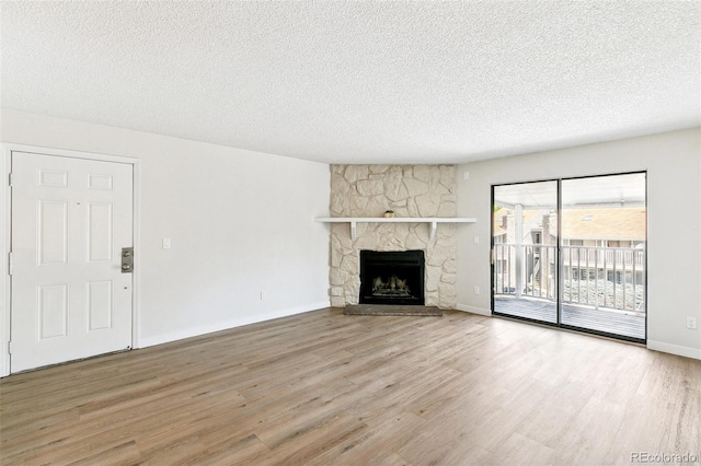 18302 E Kepner Pl Unit 207, Aurora, CO 80017 - unfurnished living room with wood finished floors, a textured ceiling, and a stone fireplace