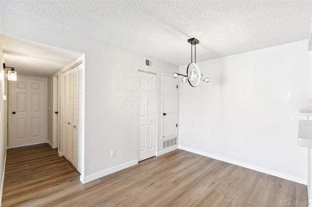 18302 E Kepner Pl Unit 207, Aurora, CO 80017 - unfurnished dining area featuring light wood-style flooring, a chandelier, and a textured ceiling