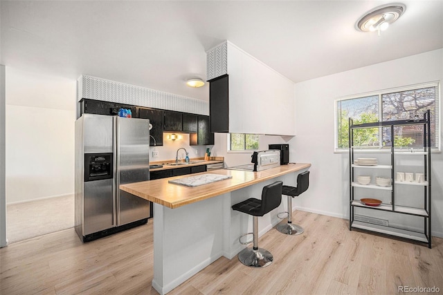 12289 W Atlantic Ave, Lakewood, CO 80228 - kitchen featuring stainless steel fridge, wood counters, light wood-style flooring, and a breakfast bar area
