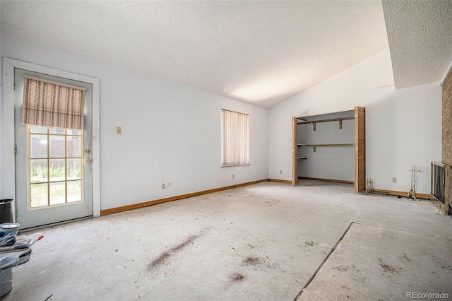 12289 W Atlantic Ave, Lakewood, CO 80228 - unfurnished living room with a textured ceiling, lofted ceiling, concrete floors, and baseboards