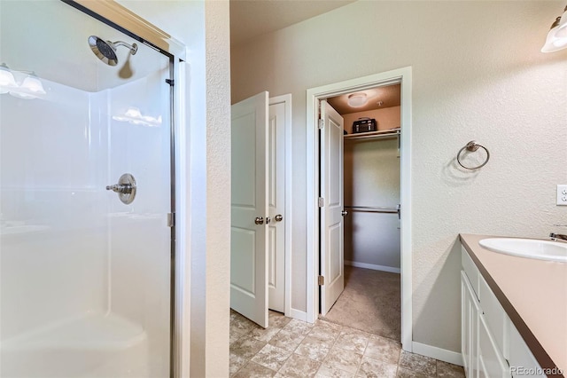 6024 W 1st St Unit 30, Greeley, CO 80634 - bathroom with a shower stall, vanity, a spacious closet, and a textured wall