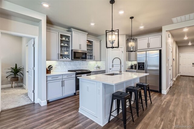 13460 Broad Wing Ave, Parker, CO 80134 - kitchen with appliances with stainless steel finishes, a sink, a kitchen bar, tasteful backsplash, and dark wood-type flooring