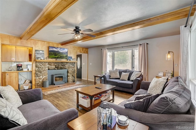 living area featuring a ceiling fan, beamed ceiling, and wood finished floors