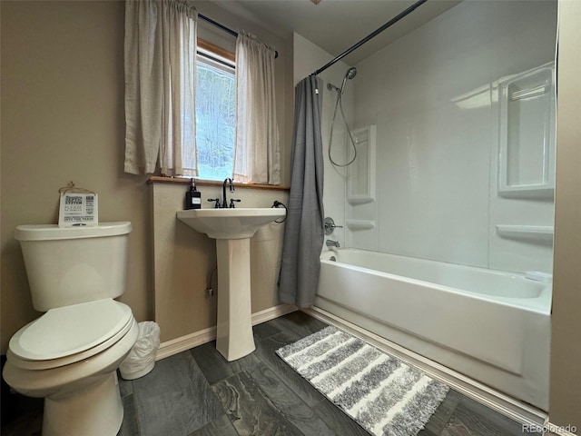 bathroom featuring toilet, baseboards, and shower / tub combo