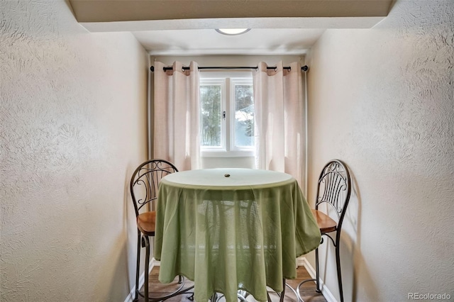 dining space with baseboards and a textured wall