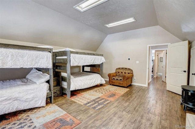 bedroom featuring baseboards, wood finished floors, and vaulted ceiling