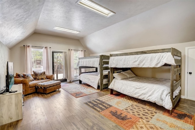 bedroom featuring a textured ceiling, lofted ceiling with skylight, and wood-type flooring