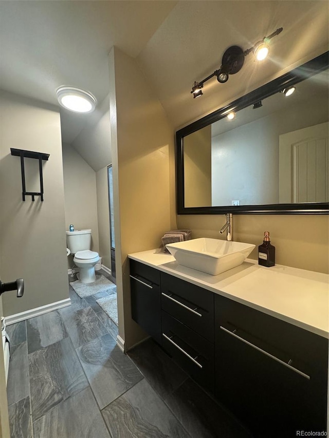 full bathroom featuring toilet, baseboards, vanity, and vaulted ceiling