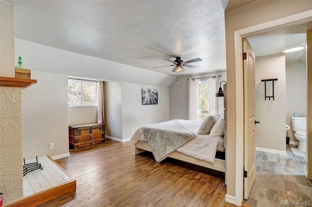 bedroom featuring lofted ceiling, baseboards, light wood-style flooring, and a ceiling fan