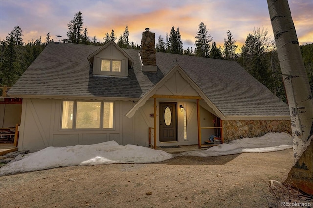 view of front of property with board and batten siding, roof with shingles, and a chimney