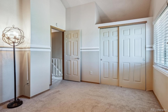 unfurnished bedroom featuring multiple windows, light carpet, a closet, and vaulted ceiling