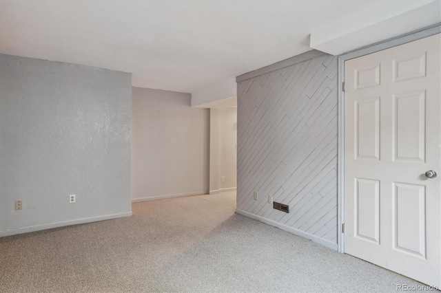 carpeted empty room featuring wood walls