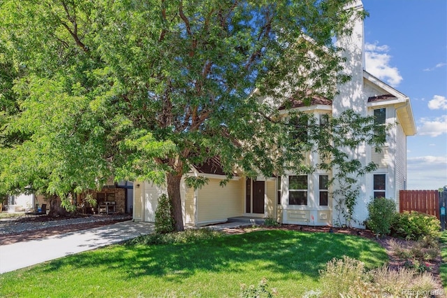 view of property hidden behind natural elements with a garage and a front lawn