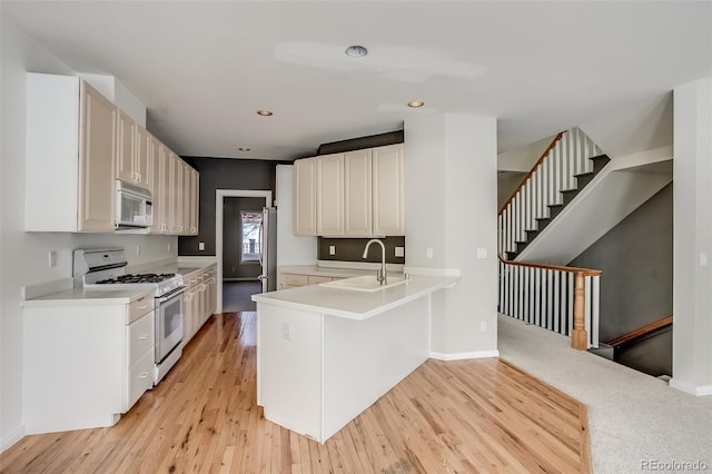 kitchen featuring white appliances, white cabinetry, sink, kitchen peninsula, and light hardwood / wood-style flooring