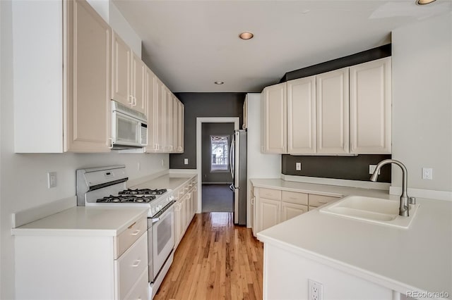 kitchen featuring light hardwood / wood-style floors, sink, white appliances, and white cabinetry