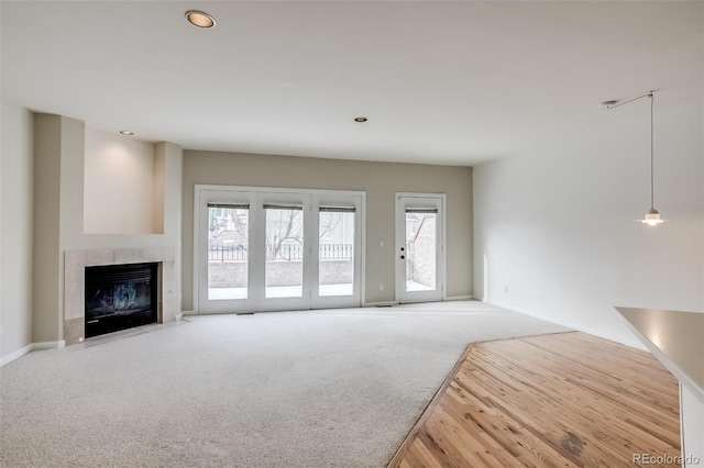 unfurnished living room featuring carpet flooring and a tiled fireplace