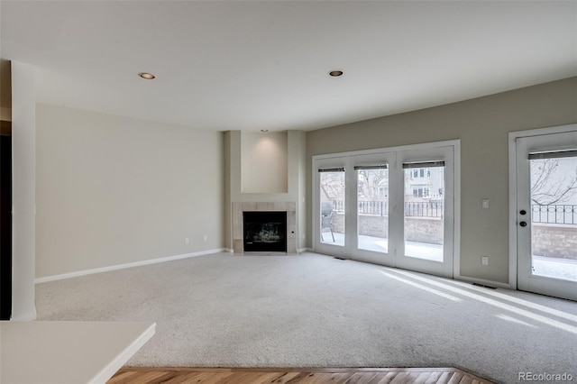 unfurnished living room featuring light colored carpet and a tiled fireplace