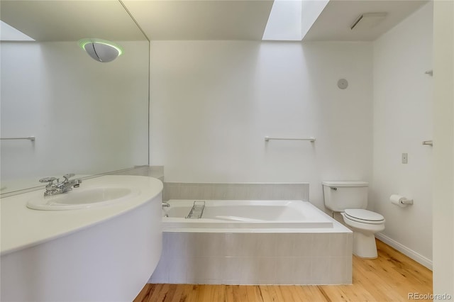 bathroom featuring toilet, a skylight, hardwood / wood-style flooring, a relaxing tiled tub, and sink