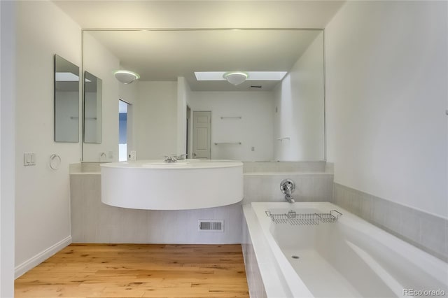 bathroom featuring a bath, sink, and wood-type flooring