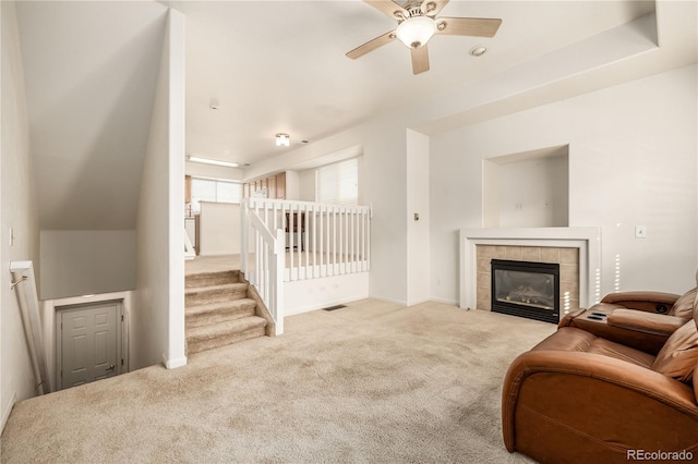 carpeted living room with a tile fireplace and ceiling fan