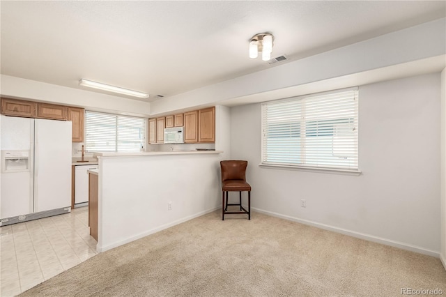 kitchen with kitchen peninsula, light carpet, and white appliances