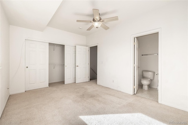 unfurnished bedroom with a closet, ensuite bathroom, ceiling fan, and light colored carpet