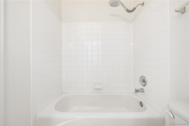 bathroom with tiled shower / bath combo and toilet