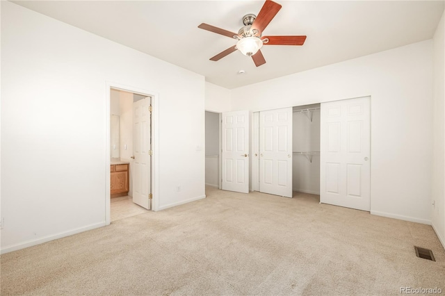 unfurnished bedroom featuring ensuite bathroom, ceiling fan, light colored carpet, and a closet