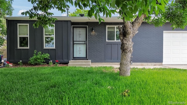 5170 Deephaven Ct, Denver, CO 80239 - view of front of property with board and batten siding, a garage, a front lawn, and brick siding