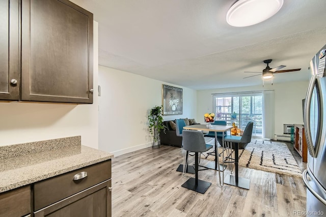610 S Clinton St Unit 8C, Denver, CO 80247 - dining area with light wood-style floors, a ceiling fan, and a baseboard radiator