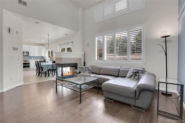 10540 Tracewood Cir, Highlands Ranch, CO 80130 - living room featuring light wood-style floors, a tiled fireplace, and a high ceiling