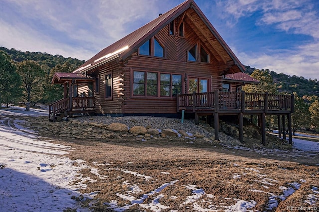 snow covered back of property featuring a wooden deck