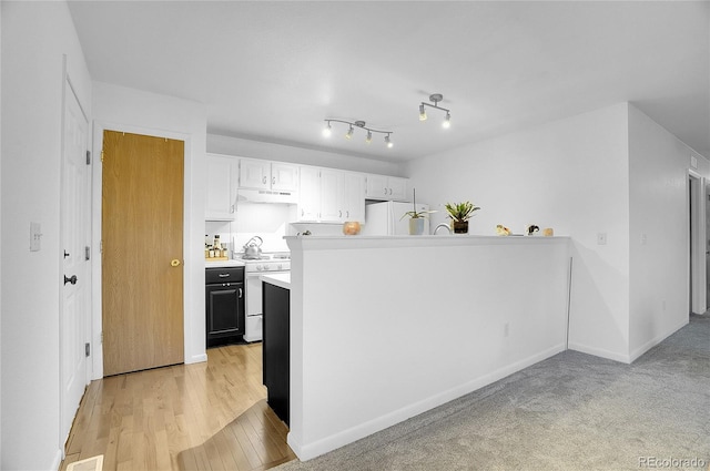 kitchen with white appliances, kitchen peninsula, light wood-type flooring, and white cabinets