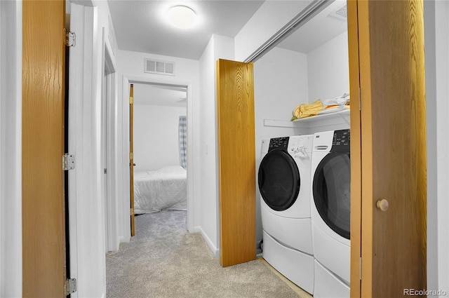 clothes washing area featuring washer and clothes dryer and light carpet