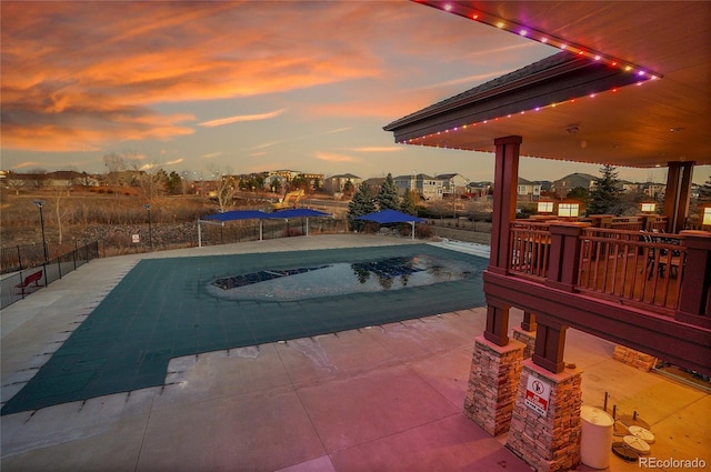 pool at dusk featuring a patio area and a trampoline