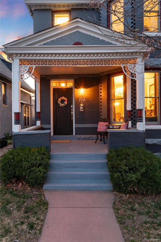 property entrance with covered porch and brick siding